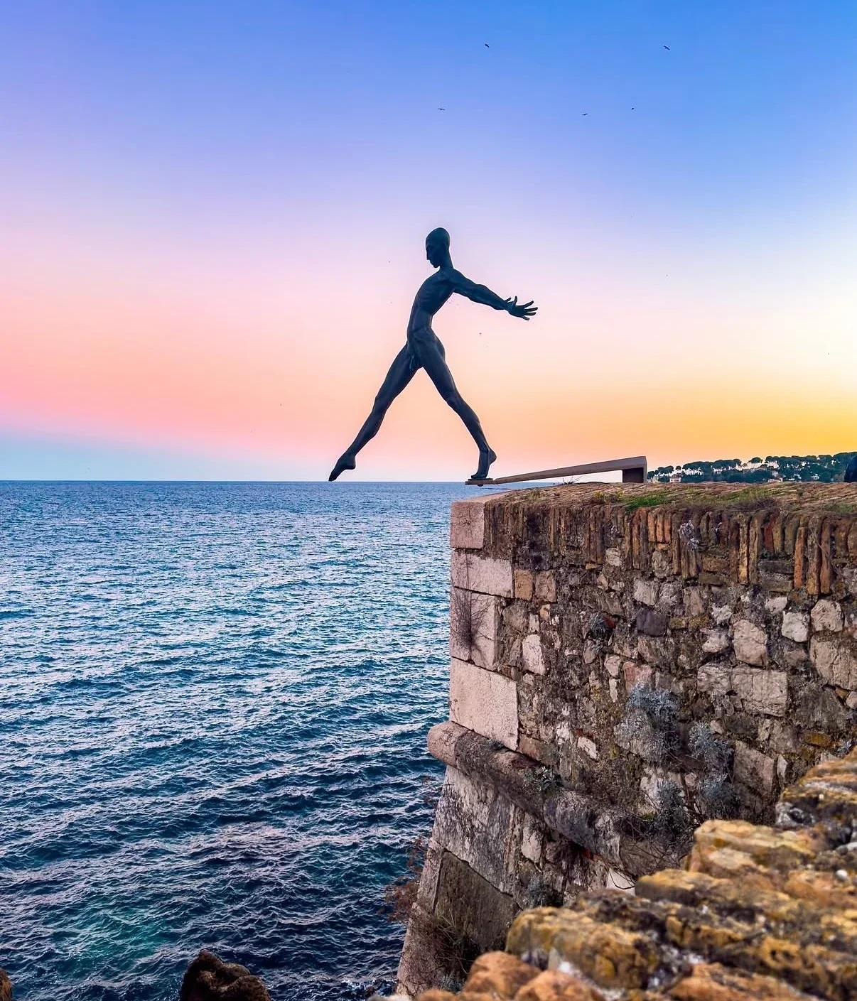 Sculpture above the sea and stone ramparts in Antibes at sunset