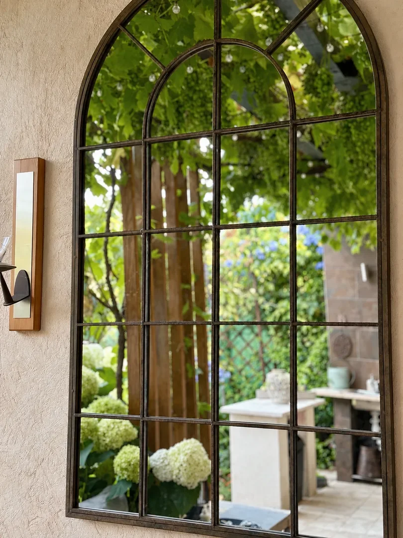 Arched mirror reflecting the shaded garden terrace at Villa Augflor